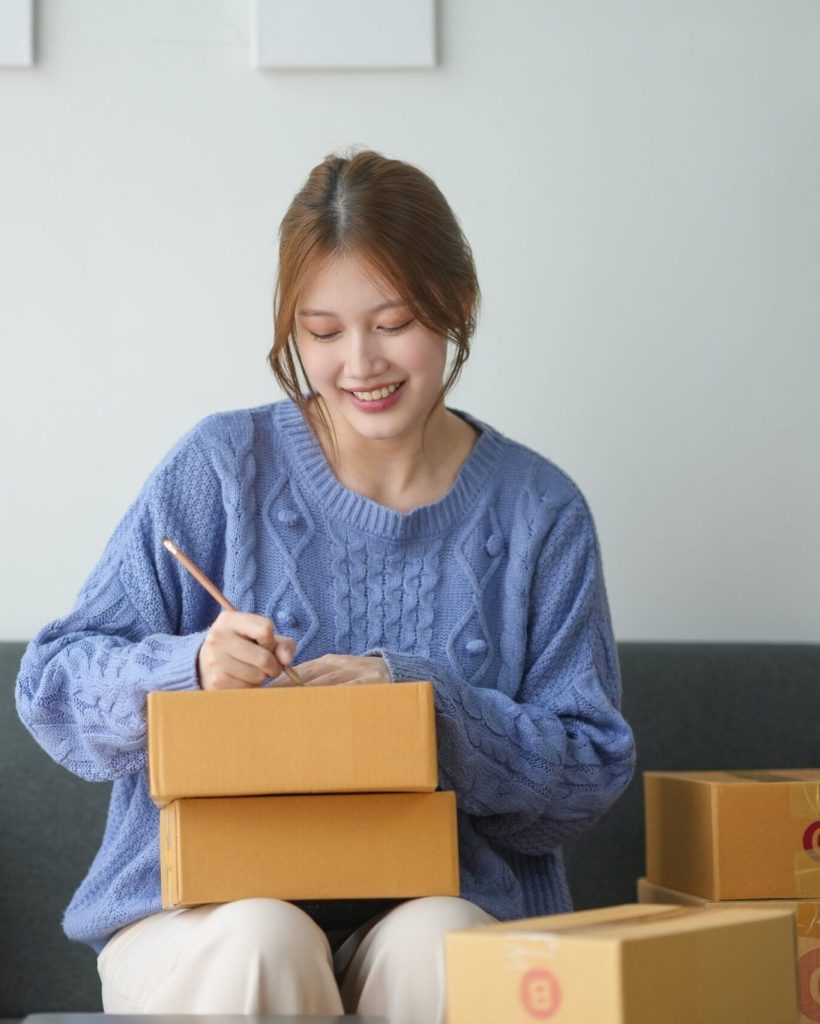 woman-packing-boxes-for-shipping-sitting-on-a-cou-2024-06-11-20-38-01-utc-min