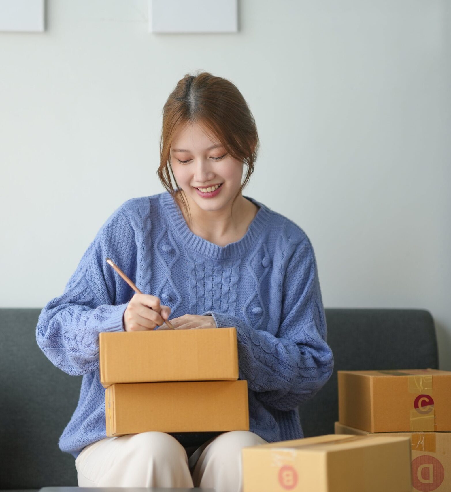 woman-packing-boxes-for-shipping-sitting-on-a-cou-2024-06-11-20-38-01-utc-min